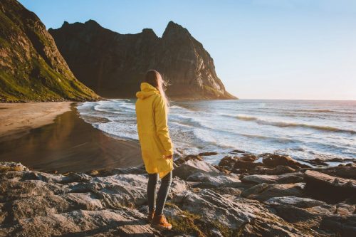 Woman,In,Yellow,Raincoat,Walking,Alone,On,Kvalvika,Beach,In