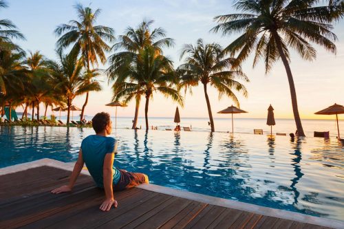 Happy,Holidays,In,Beautiful,Beach,Hotel,At,Sunset,,Man,Sitting